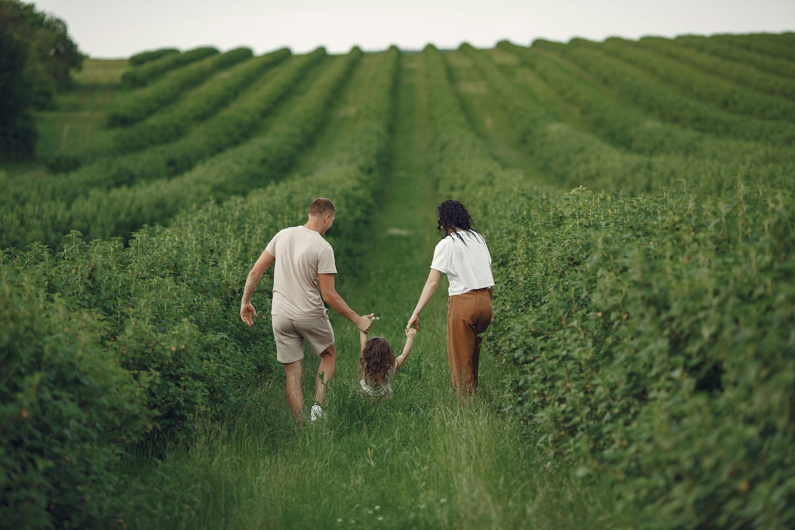 Happy family walking together through a lush green field enjoying nature and togetherness.